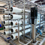 Reverse osmosis water treatment system with multiple filtration tubes in factory setting.